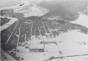 26日夜11時ごろ水防団が円山川の破堤を防ぐべく必死の努力を行っていたところ突然下流左支川奈佐川が決壊した
あふれだした濁流は国鉄山陰線を越えてさか上り豊岡市内にどっとなだれこんだ（豊岡市街地中心部）