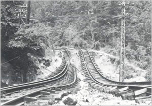 神戸電鉄菊水駅～鈴蘭台駅間の路床が新湊川の増水で洗掘され曲りくねったレール（神戸市北区付近)